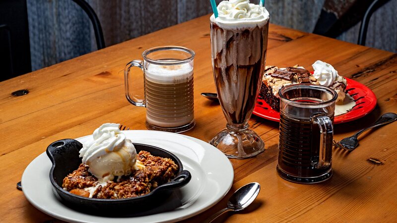 Table with OMG apple crisp, s'mores brownie with a milkshare, coffee and cappuccino
